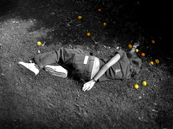 Oranges on the ground surrounded by dark grass