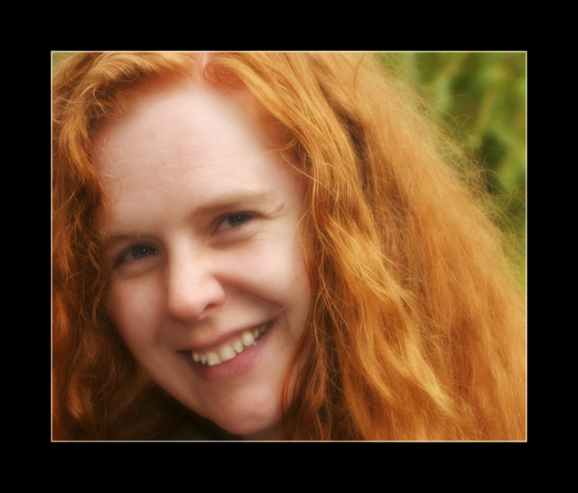 Long red curly hair and a bright smile