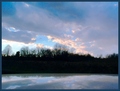 winter's clouds reflected by a newly frozen farm pond