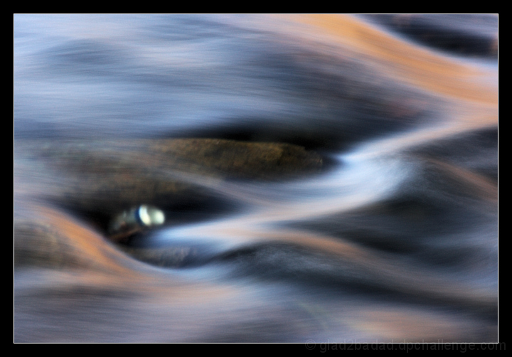 Beneath the flow, a silver can glows - a sign of mans' trespass.