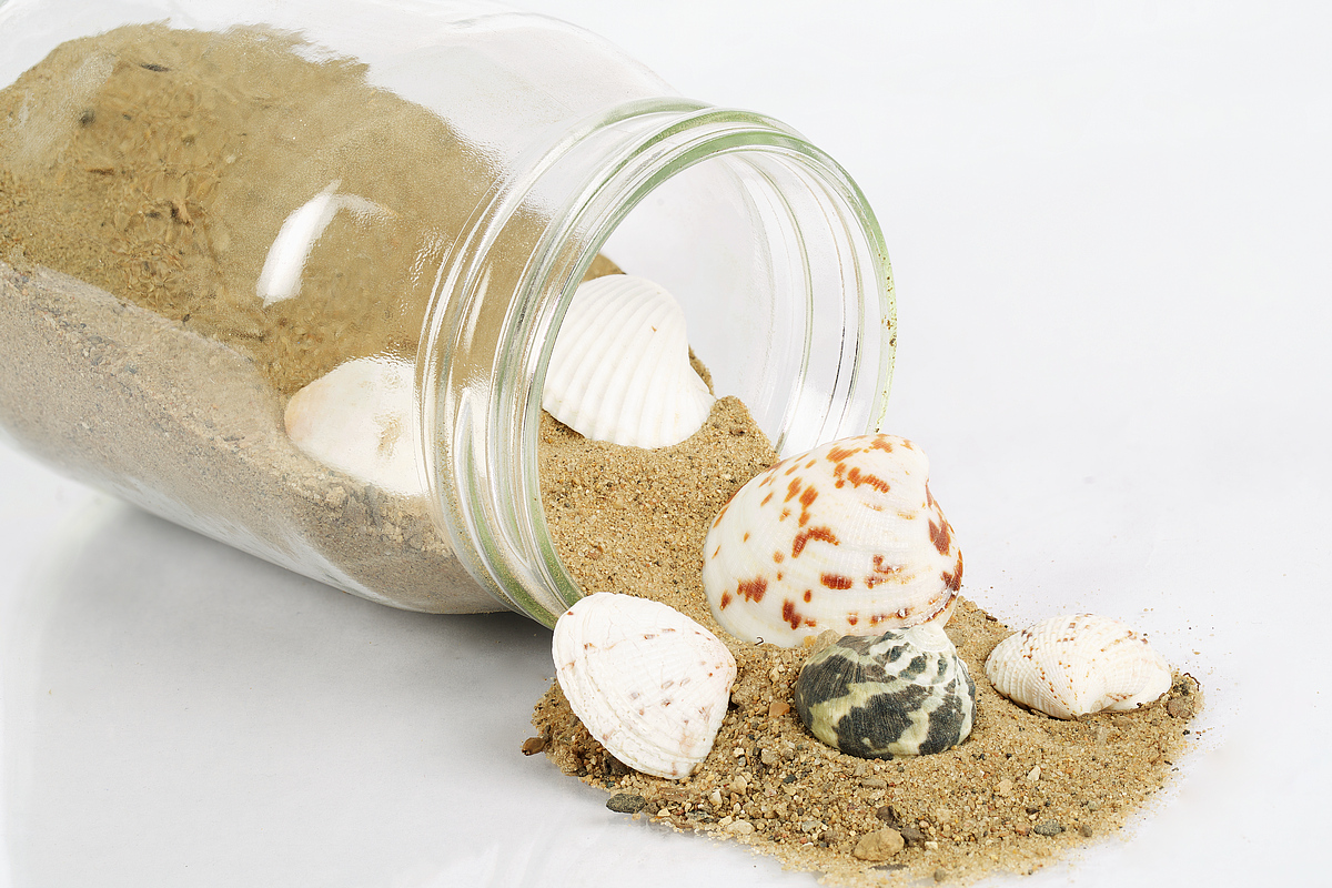 Glass Jar, Pouring Sand and Shells onto White Surface