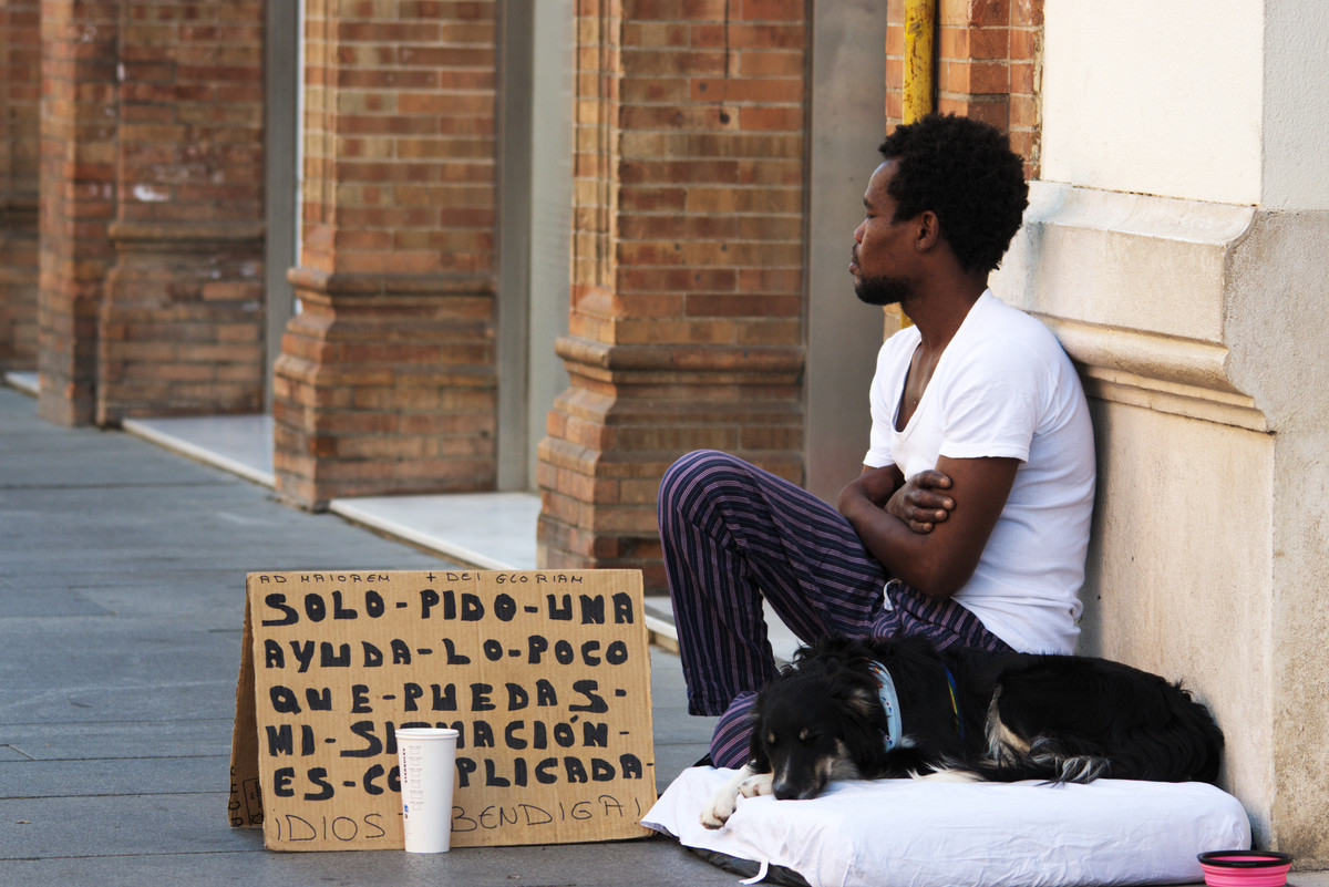 Black beggarman with dog asking for alms