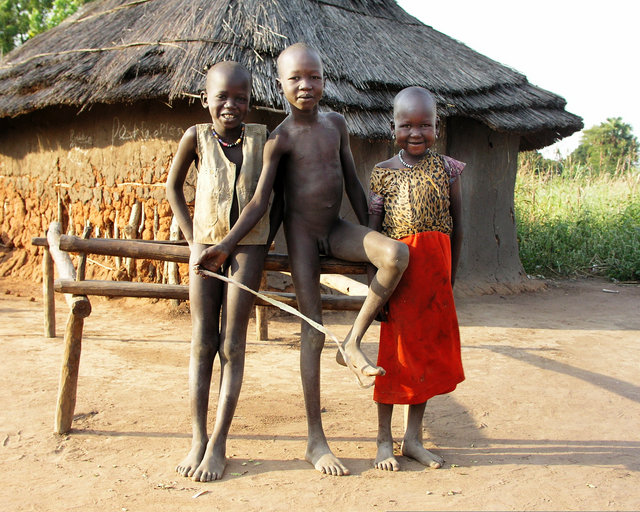 Three Kids In Front of a Hut